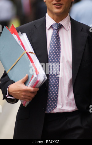 Paperwork, young office workers carrying a manila folder full of documents walking in the street, City of London, England 2009  2000s UK HOMER SYKES Stock Photo
