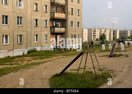 Deserted playground outside social housing apartment blocks, Karabash, Urals, Russia Stock Photo