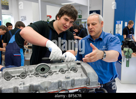 Master explaining to an apprentice while working on an engine in the BMW training center for automotive mechatronics, Munich, B Stock Photo