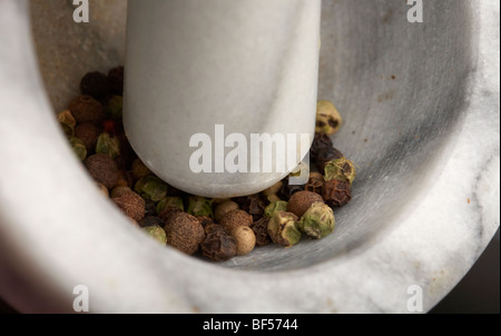 crushing mixed peppercorns with pestle in the bottom of a mortar for grinding for cooking Stock Photo