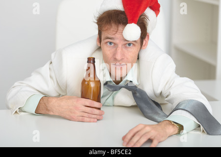 The young man in a Christmas hat at office with a beer bottle Stock Photo