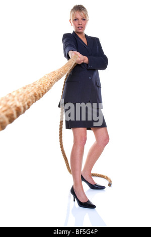 Blonde businesswoman pulling on a piece of rope, focus on her. Isolated on a white background. Stock Photo