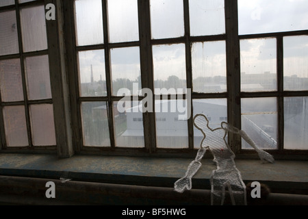 Yekaterinburg seen through dirty windows of factory, Russia. Man-like figurine made from bubble wrap sitting on ledge Stock Photo