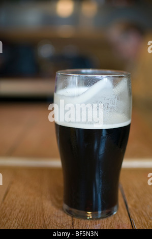 A pint of stout real ale sitting on a pub table Stock Photo