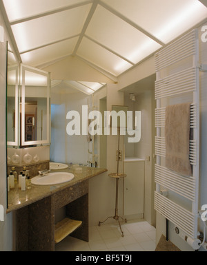 Opaque glass panels in apex ceiling in modern cream bathroom with vertical wall-mounted radiator Stock Photo
