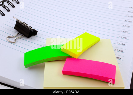 open personal organizer, multicolor post-its and black steel clip Stock Photo