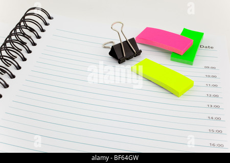 open personal organizer, multicolor post-its and black steel clip Stock Photo