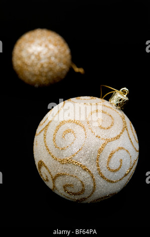 Close up of gold coloured decorative bauble with out of focus bauble behind on black background Stock Photo