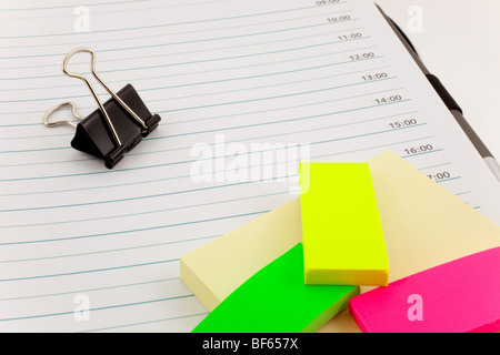 open personal organizer, multicolor post-its and black steel clip Stock Photo