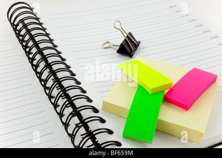 open personal organizer, multicolor post-its and black steel clip Stock Photo