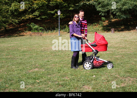 Young couple with pram in park on a summer autumn day Stock Photo