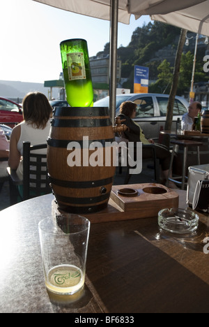 A glass of cider at a cafe in Luarca, northern Spain. In the background is an upturned cider bottle placed in a dispenser. Stock Photo