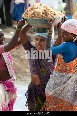 Indian woman working on the roads, lifting and carrying sand in a bowl. Puttaparthi, Andhra Pradesh, India Stock Photo
