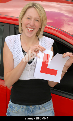 Young woman ripping up L plate after passing her driving test Stock Photo