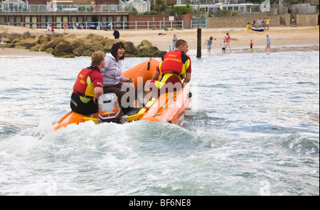 A woman is rescued from a boat by RNLI lifeguards, to be put ashore at Sandbanks, Poole, Dorset. UK. Stock Photo