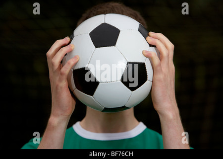 soccer football player holding ball in front of his face Stock Photo