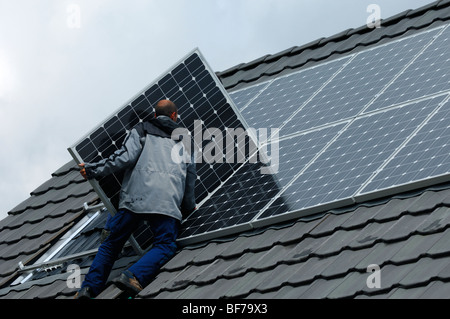 workmen installing photovoltaic solar panels on the roof of a private house Stock Photo