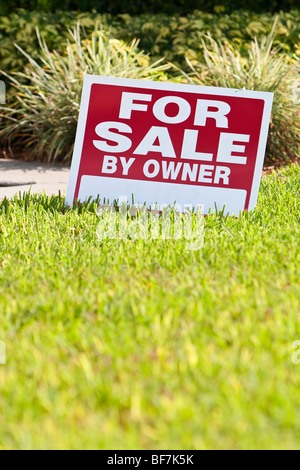 House for sale by owner sign on the front lawn of a house Stock Photo