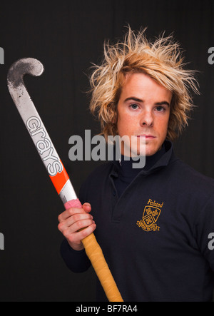 Head and shoulders portrait of a determined young man wearing a hockey shirt and holding a stick. UK, Britain Stock Photo