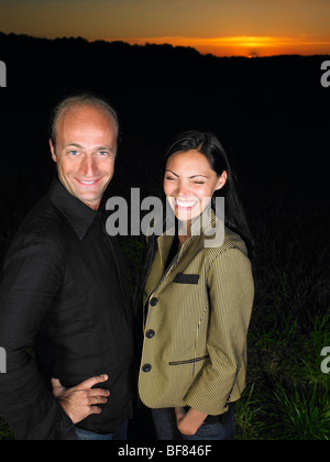 Friends laughing in a field, by night Stock Photo