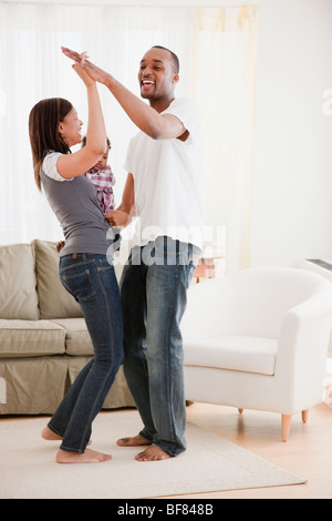 African couple and baby dancing in living room