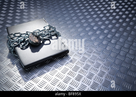 Laptop in chains on metal back ground Stock Photo