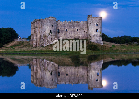 The moon rising behind Carew Castle beside the Carew River at Carew, Pembrokeshire, Wales Stock Photo