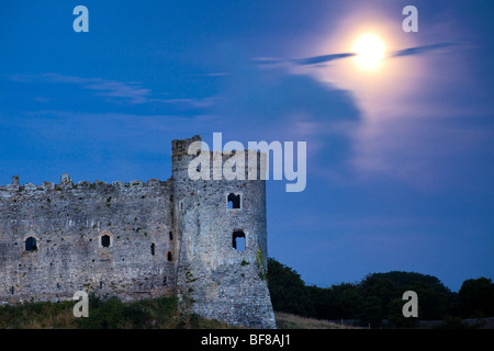 The moon rising over Carew Castle beside the Carew River at Carew, Pembrokeshire, Wales Stock Photo