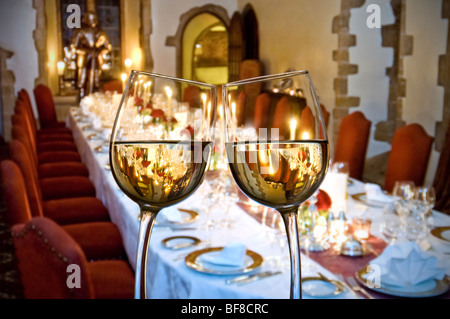 Christmas table candlelight white wine glasses toasting in foreground of a formal luxury candlelit  laid dinner party table Stock Photo