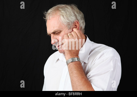 Late middle aged man holding ear lobe suffering from severe ear ache painful inner middle ear problem infection hearing problem Stock Photo