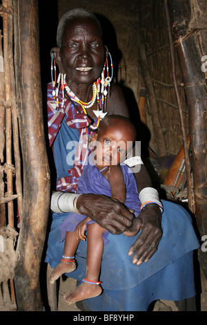 Elderly Masai Woman With Grandchild In Her Home In Engaruka Village, Rift Valley, Tanzania Stock Photo