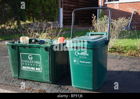 Green kerbside recycling boxes for glass and food waste waiting for collection on a kerb outside a house. Surrey England UK Britain Stock Photo