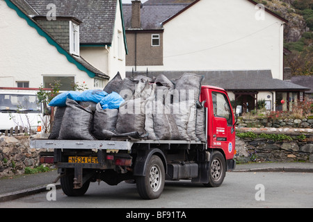 Coal merchant delivering to a house with sacks of fuel on a flatbed truck in the street. Wales, UK, Britain Stock Photo