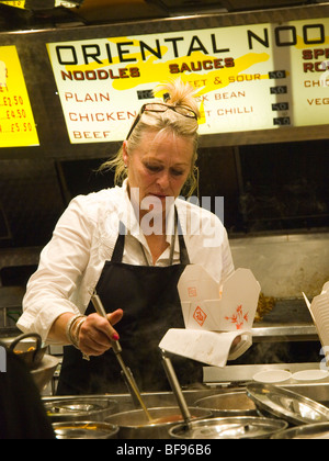 A woman serving oriental food from a refreshments stall at Goose Fair in Nottingham, Nottinghamshire England UK Stock Photo