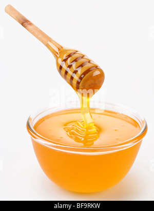 Honey pouring from stick to the bowl Stock Photo