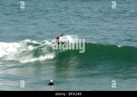 A partially submerged cameraman operates his waterproof camera system to catch action photos during surfing competition. Stock Photo