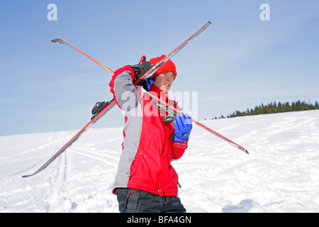 teenage boy carrying his skis his own way Stock Photo