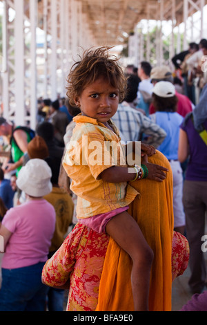 Small child riding on mother's shoulders at the Camel Fair in Pushkar India Stock Photo