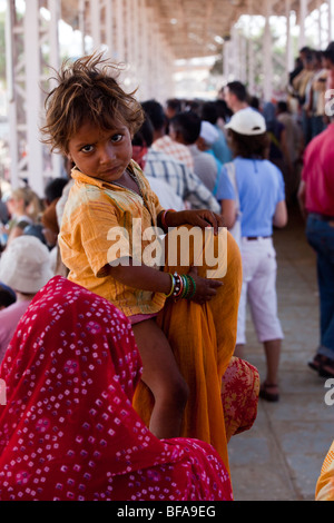 Small child riding on mother's shoulders at the Camel Fair in Pushkar India Stock Photo