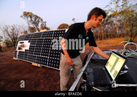 An engineer using his computer to check the amount of power generated by his the solar panels of his solar car. Stock Photo