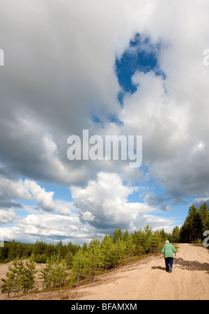 Elderly woman hiking on a sandy ridge , Finland Stock Photo