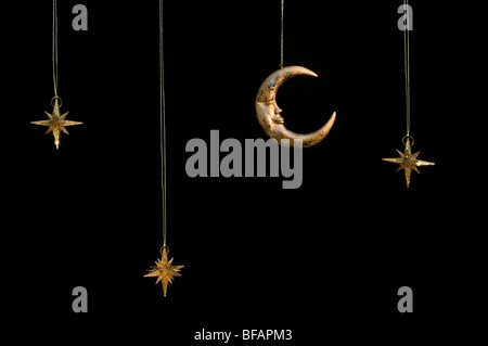 Gold shiny moon and stars sparkly hanging christmas decorations against a black background