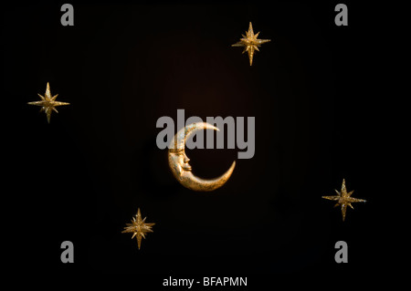Gold shiny moon and stars sparkly hanging christmas decorations against a black background