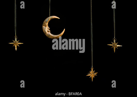 Gold shiny moon and stars sparkly hanging christmas decorations against a black background
