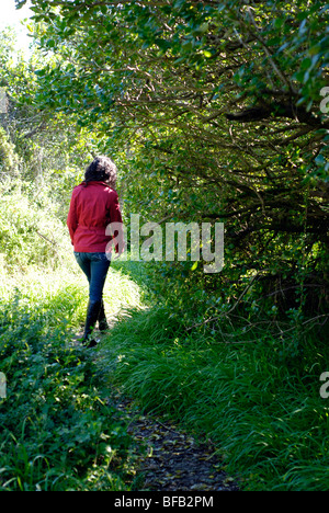 Young woman walking alone along a rural footpath. Stock Photo