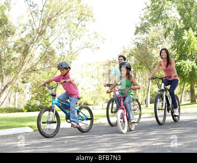 Young Family Riding Bikes In Park Stock Photo