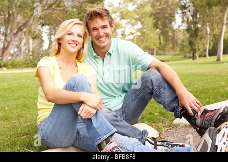 Couple Putting On In Line Skates In Park Stock Photo