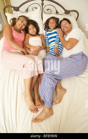 Young Family Relaxing In Bedroom Stock Photo