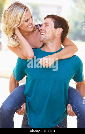 Young Man Giving Woman Piggyback Outdoors Stock Photo