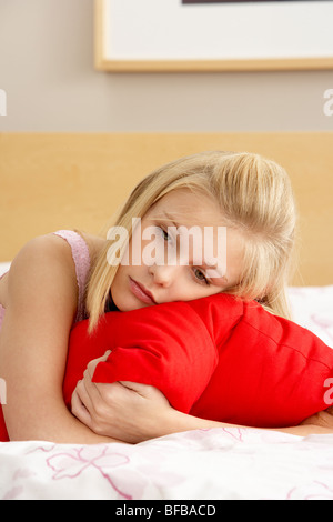 Sad Teenage Girl In Bedroom Hugging Pillow Stock Photo